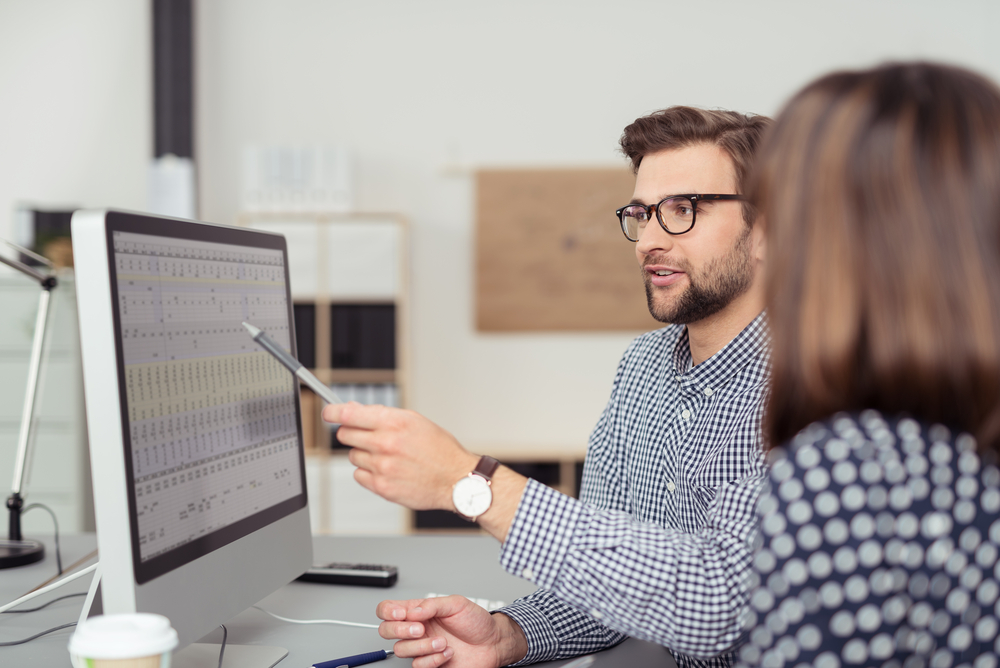 Proficient young male employee explaining a business analysis displayed on the monitor