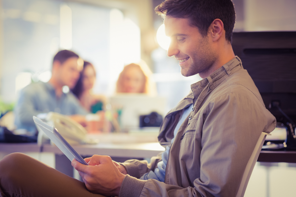 Smiling young man using digital tablet in the office